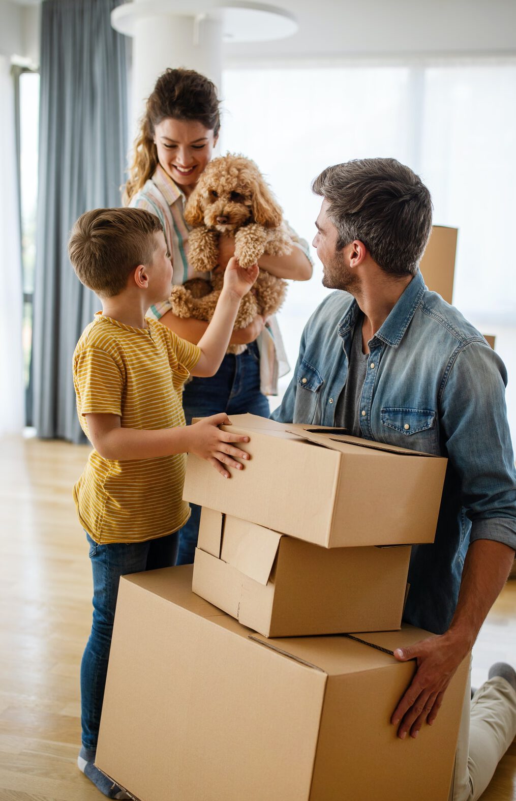 Happy family with children moving with boxes in a new apartment house