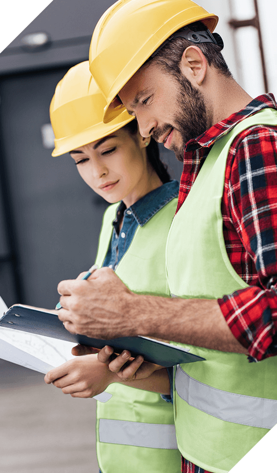 Male and Female Construction Workers Look Over Blueprint