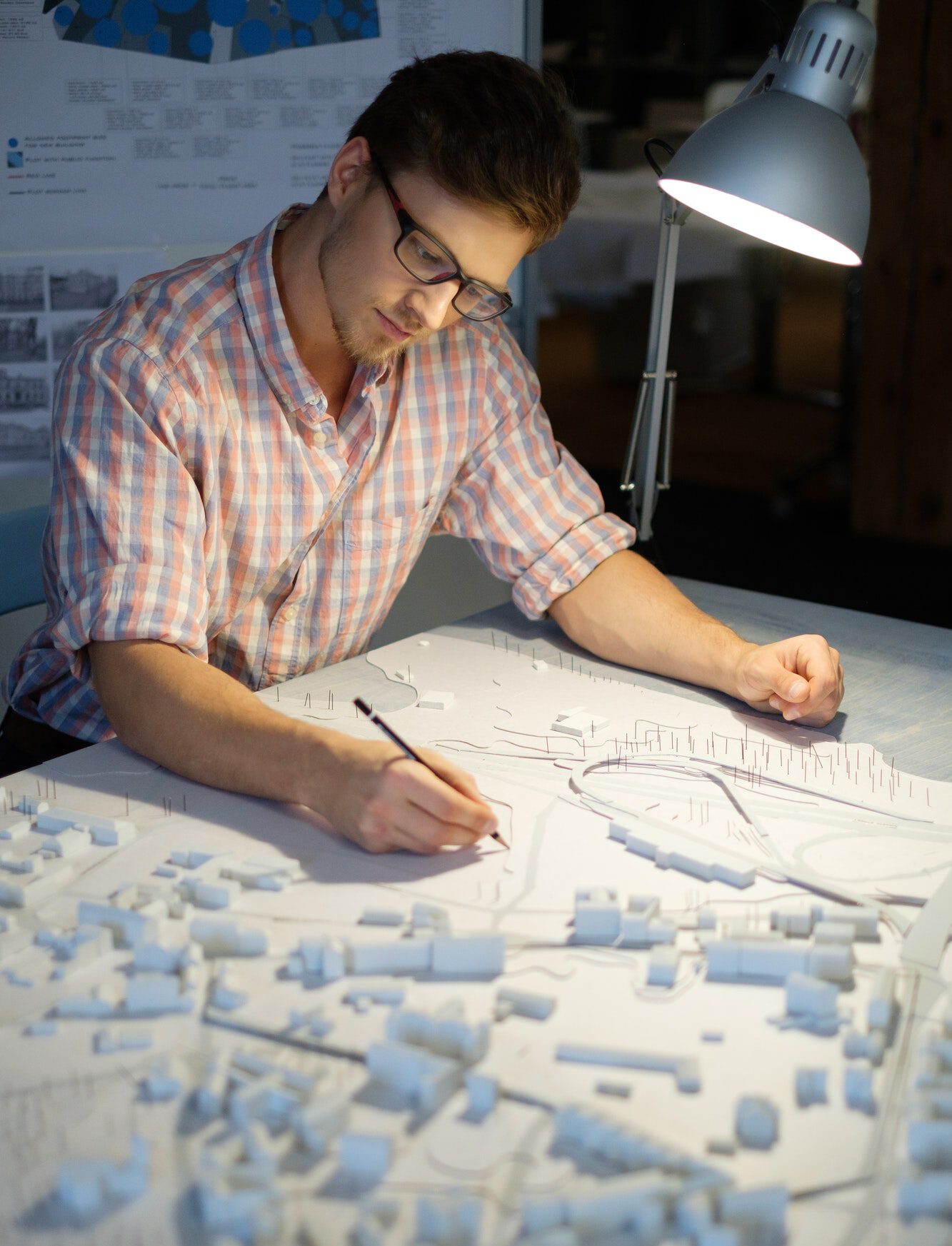 Young architect working on drawing table in architect studio.
